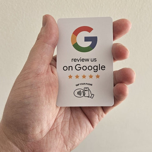 Hand holding a card with Google logo and text on a plain background